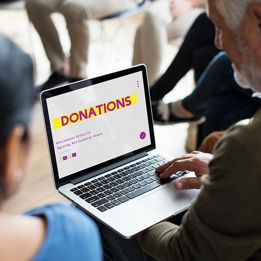 Hands typing on a laptop displaying a nonprofit donations page for fundraising-first website