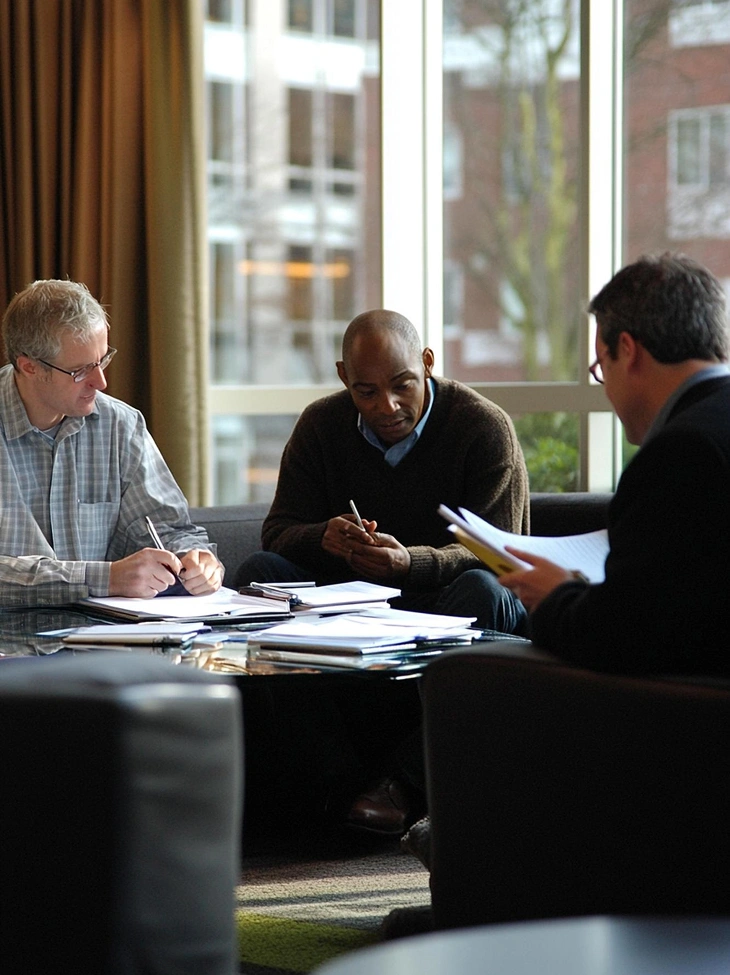Government website design team collaborating over documents in a professional office meeting